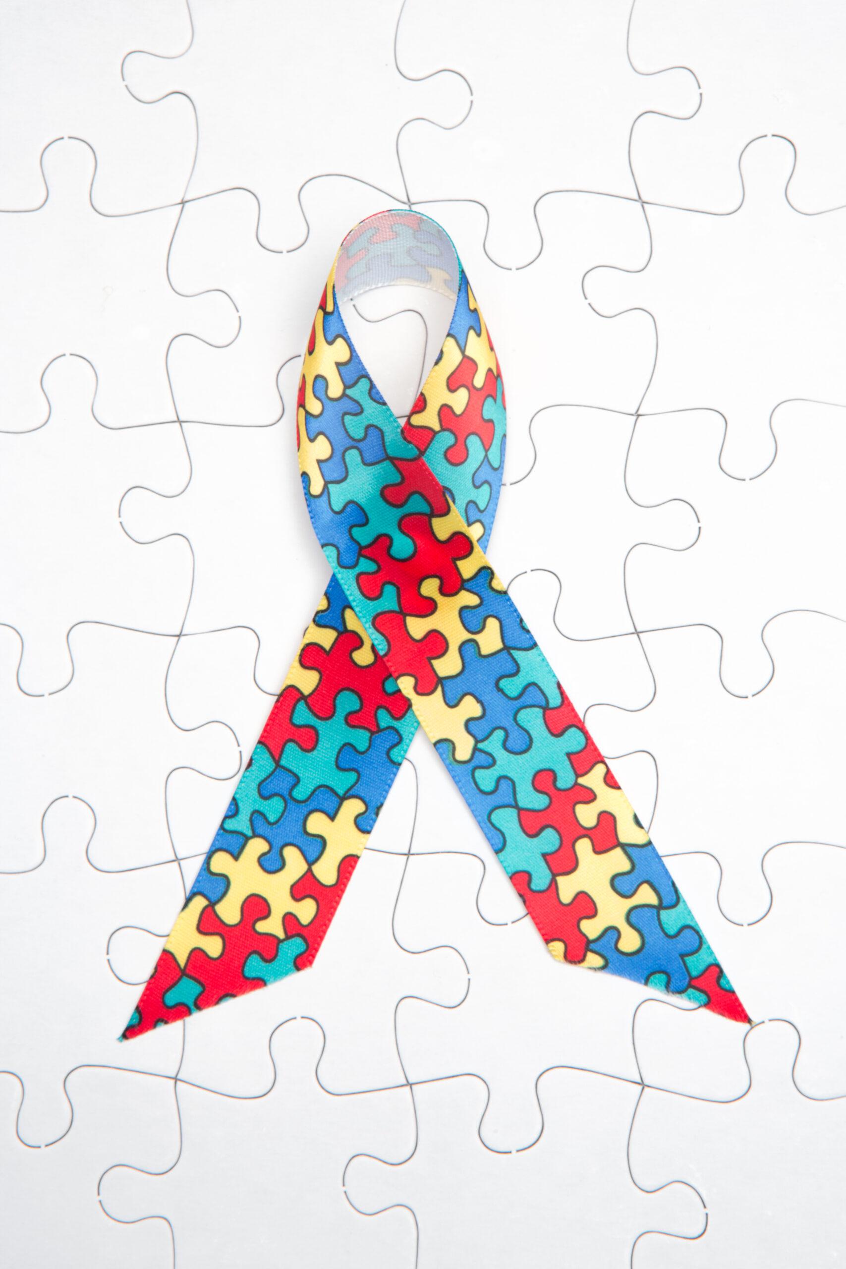 Awareness ribbon for autism and aspergers on white jigsaw background